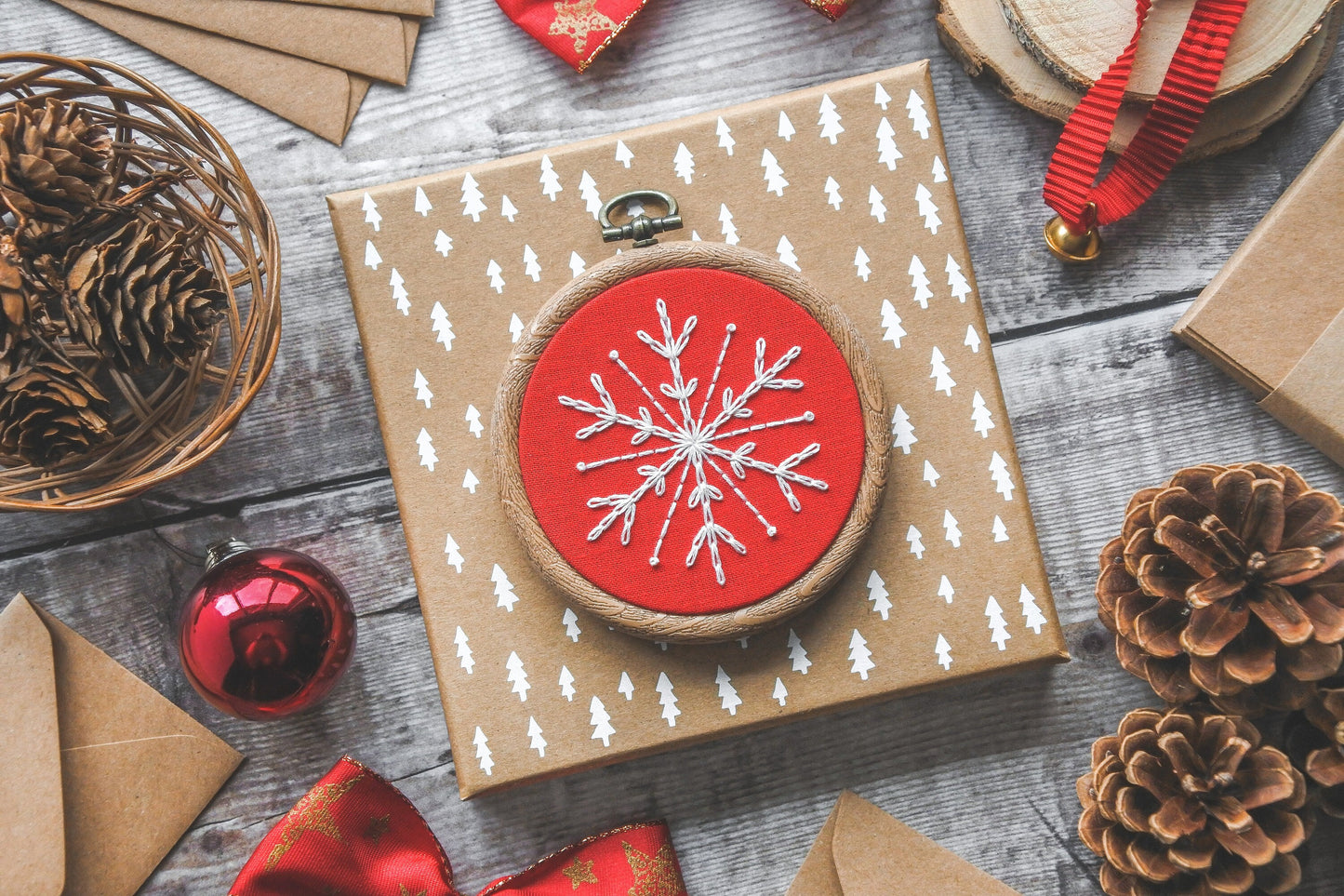 White snowflake embroidered on bright red fabric in a 3-inch wood-effect hoop