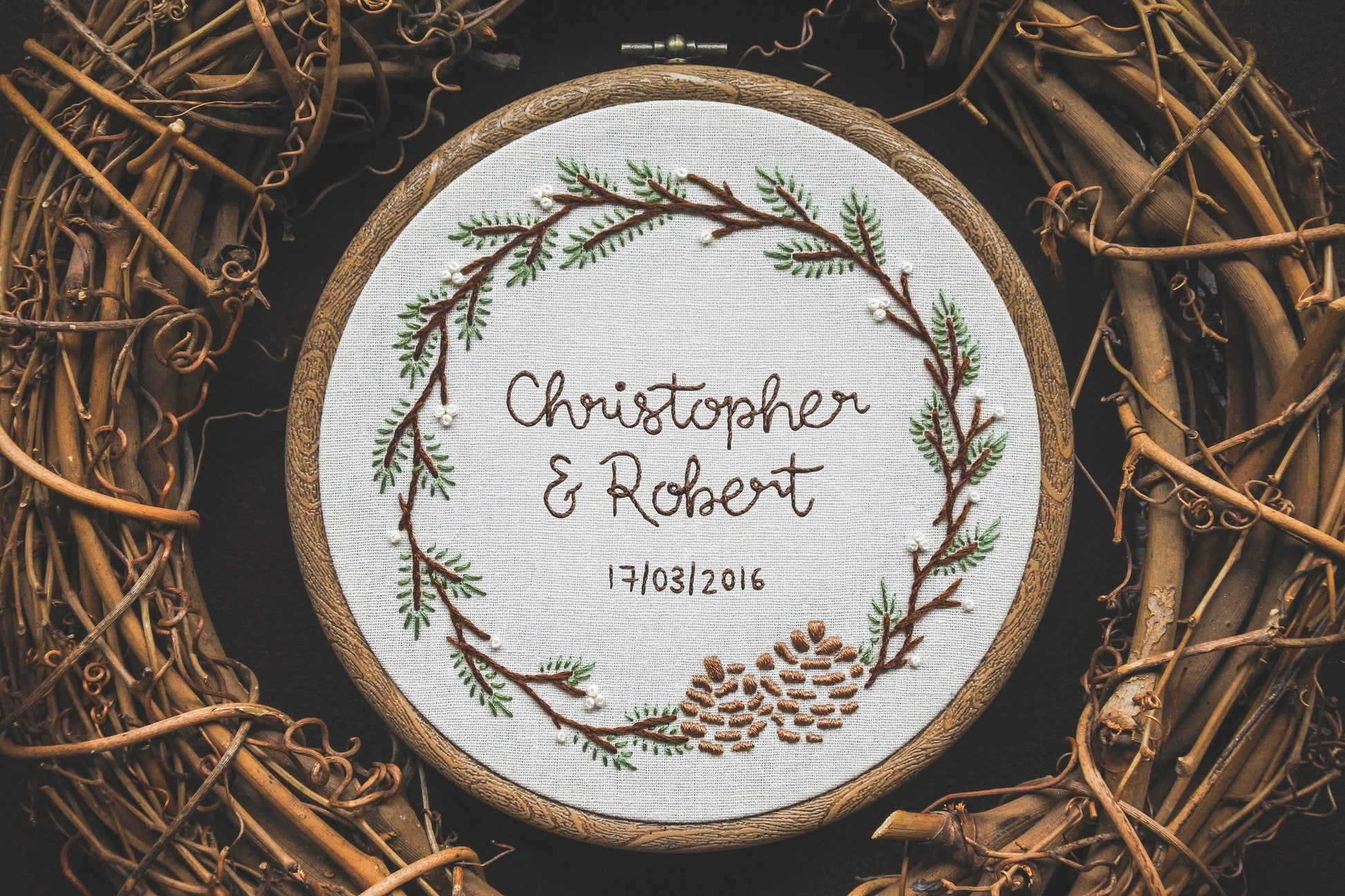 Hand embroidered winter wreath hoop with names 'Christopher and Robert' and date '17/03/2016' in the centre.